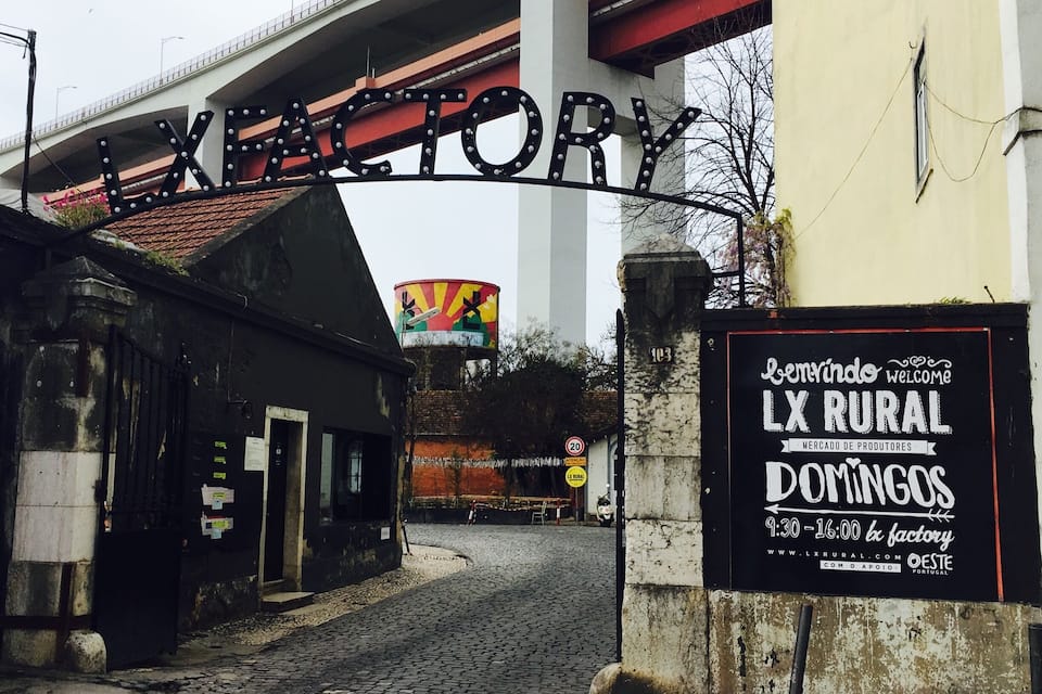 L’entrée d’un marché situé en zone rurale, avec une enseigne indiquant « LX RURAL DOMINGOS » et une grande enseigne « LXFORY » au-dessus.