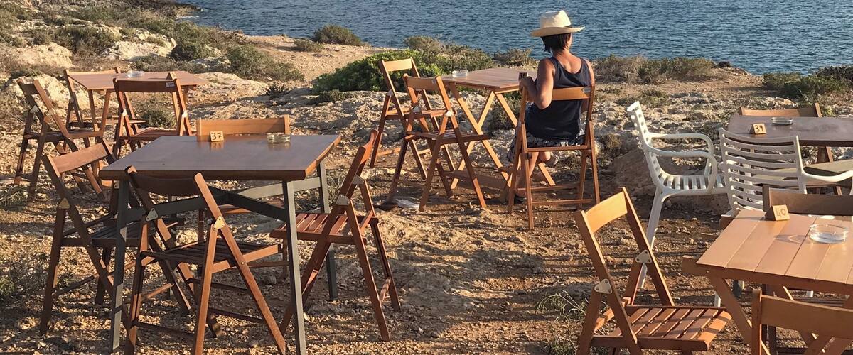 A coastal dining area with tables and chairs overlooking the sea.
