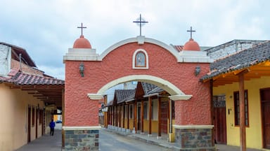 A street with a red archway, a cross on top, and a statue in the center.