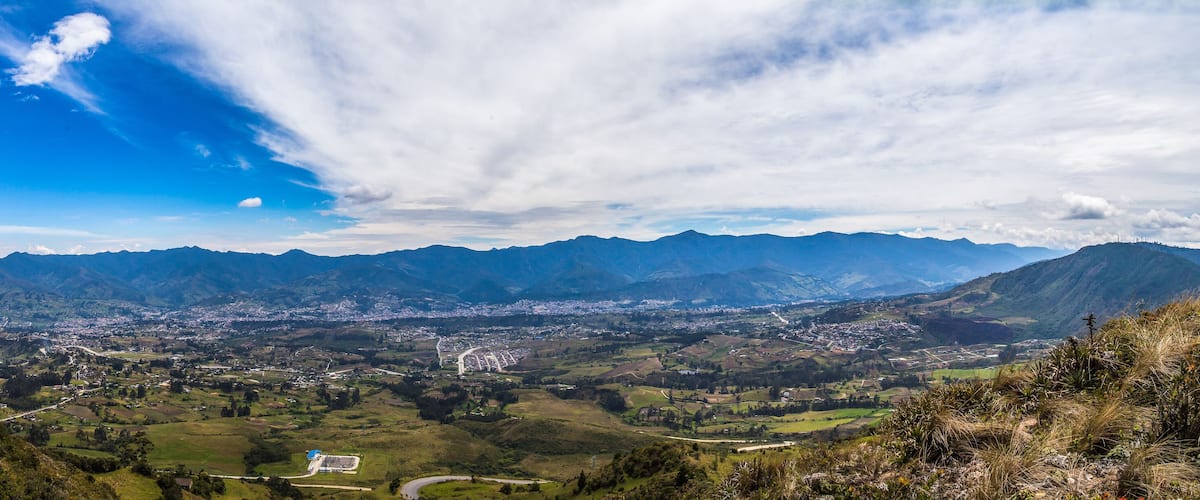 A mountainous landscape with a valley, a town, and a clear sky.