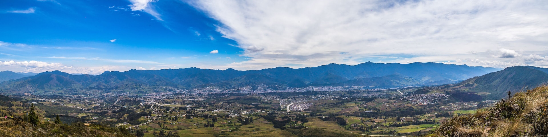 A mountainous landscape with a valley, a town, and a clear sky.