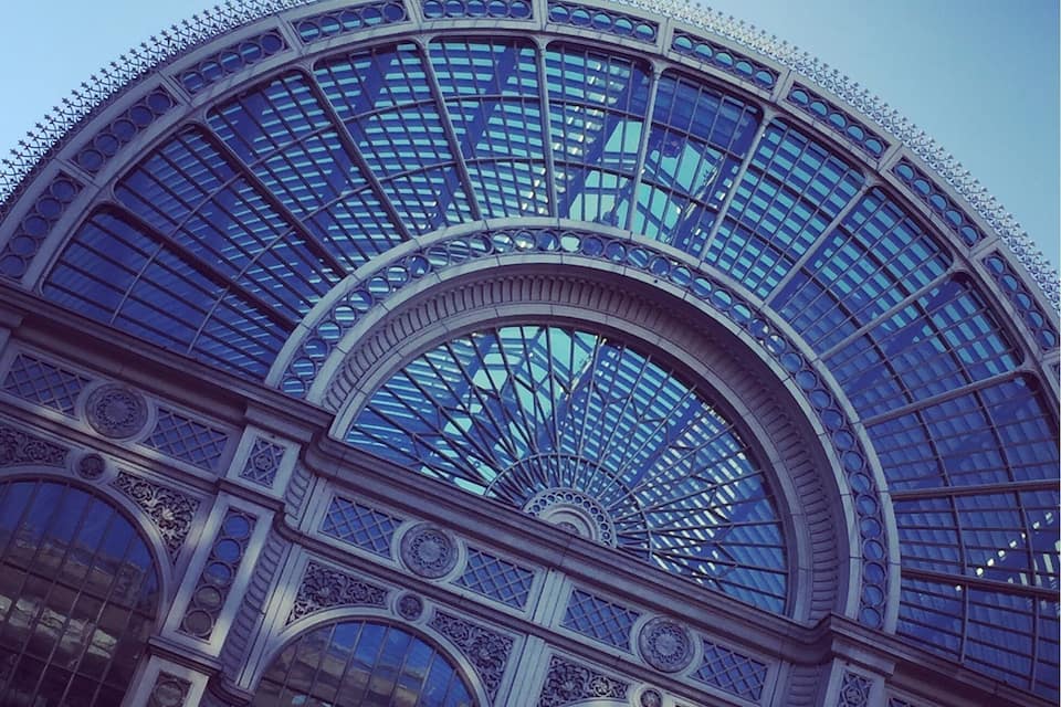 A grand arched glass roof with intricate metalwork and decorative elements.