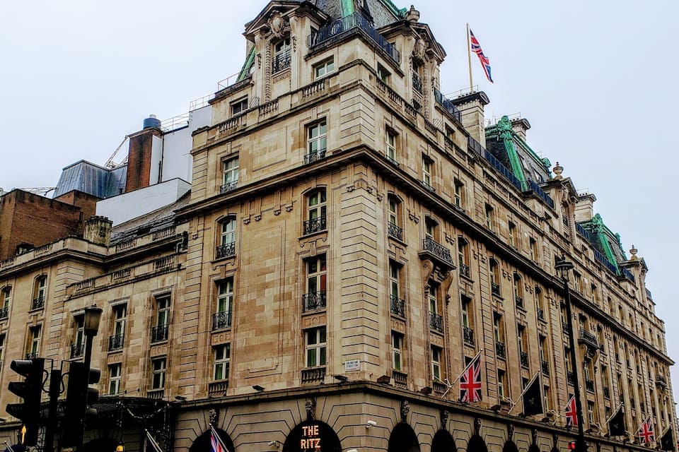 Un edificio histórico con arquitectura ornamentada, varias banderas y una entrada destacada con el letrero "The Ritz".