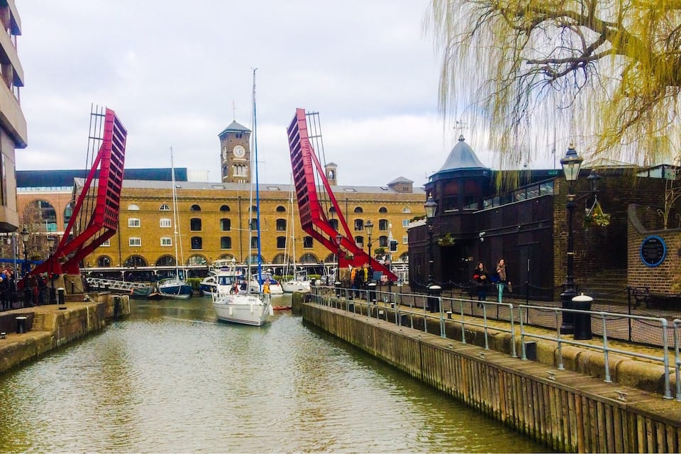 Un canal bordé de bateaux, un pont rouge et des bâtiments historiques.
