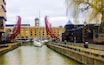 A canal with boats, a red bridge, and historic buildings.