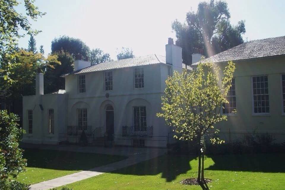 A large, two-story building with a symmetrical facade, arched windows, and a central entrance.