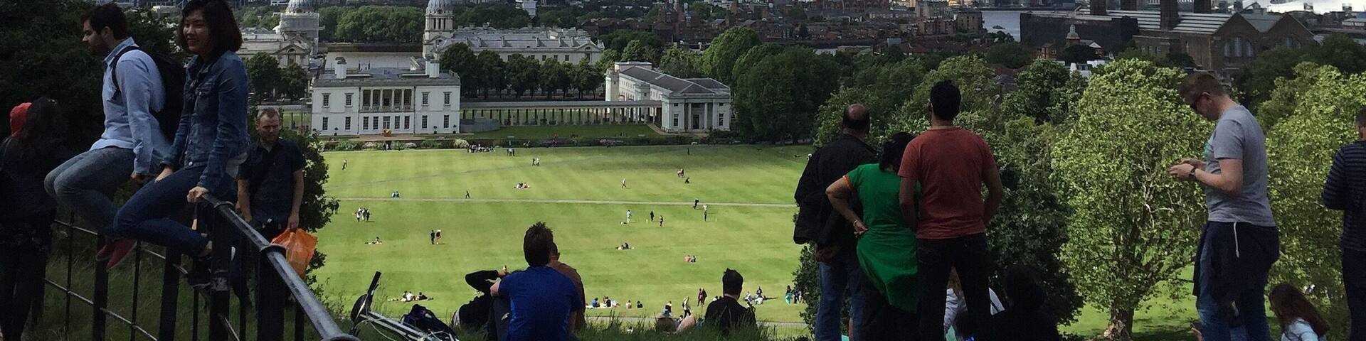 A park with people, a city skyline, and a grassy field.