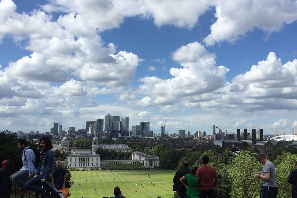Un parque con gente, el horizonte de una ciudad y un campo cubierto de césped.
