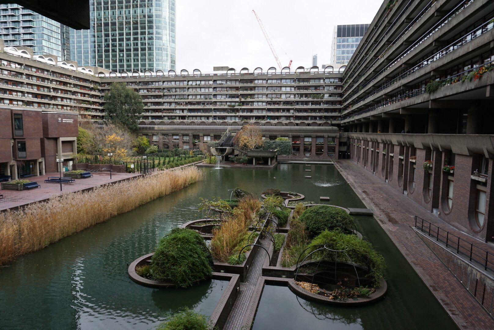Un edificio moderno en la ciudad con un patio central que incluye un canal de agua y follaje.