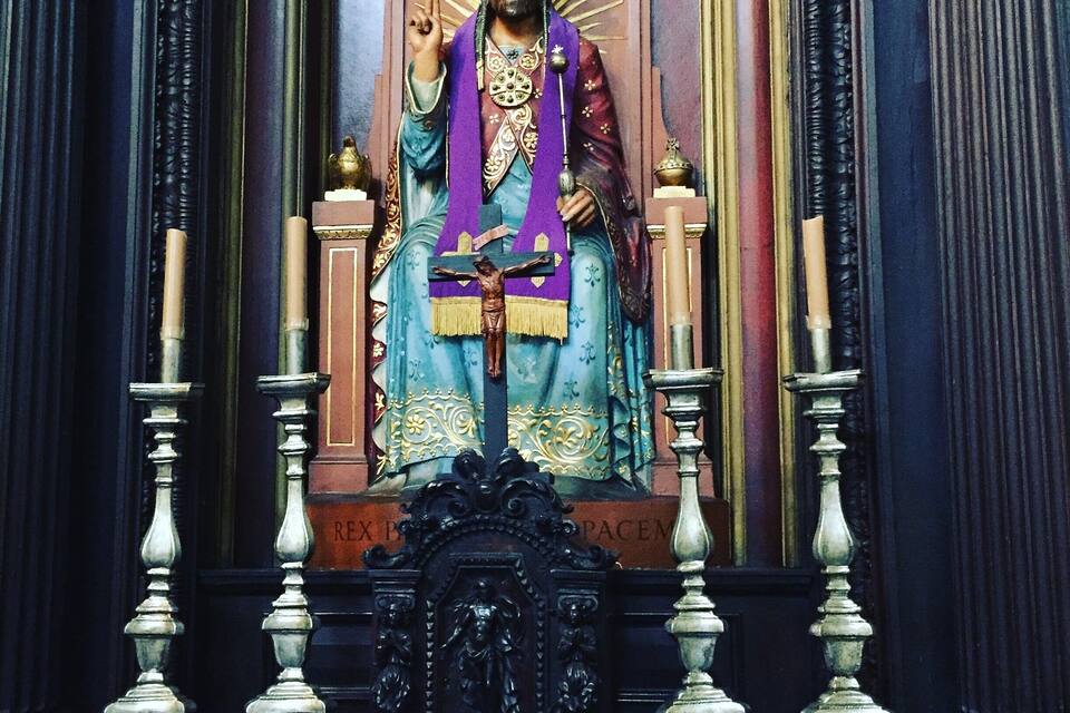A religious statue with a crown, robe, and a cross.