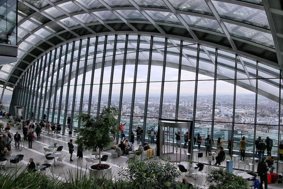 Una estructura moderna de vidrio con techo curvo que da vista a un paisaje urbano.