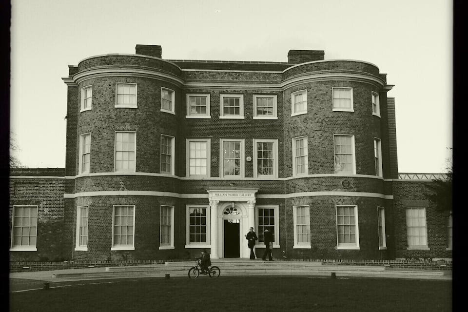 A large, multi-story brick building with a central entrance and arched windows.