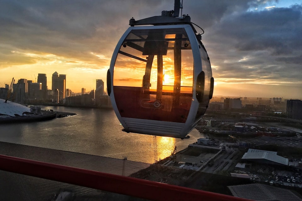 A cable car at sunset with a city skyline in the background.