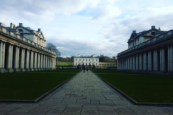 Un imposant bâtiment de style néoclassique, doté de colonnes symétriques et d’un chemin central menant à une grande structure blanche située au fond.