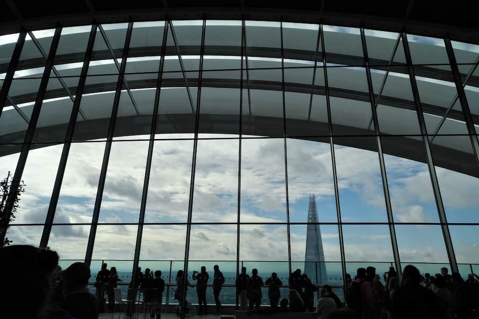 A large glass structure with a view of a tall building.