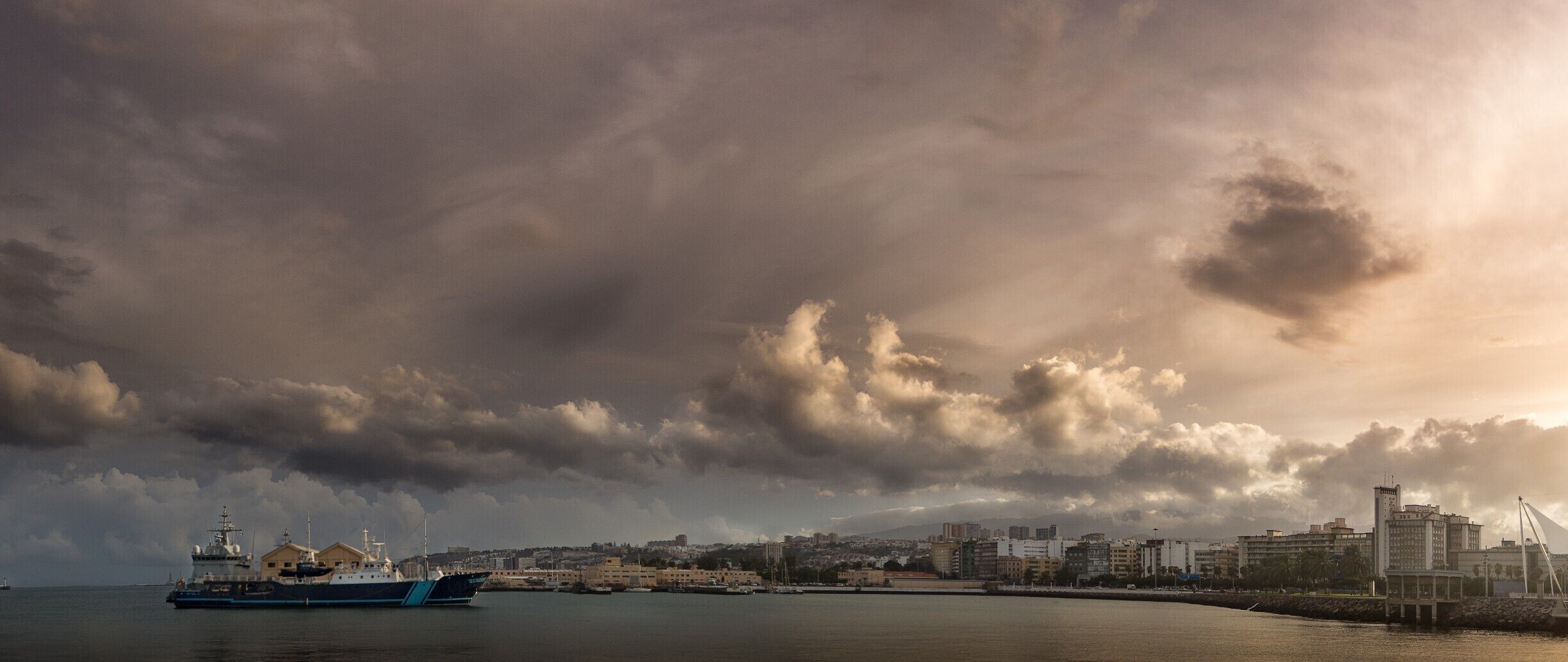 Last October we visited the beautiful island of Gran Canaria. This Island has always good weather. Not in the week we visited it. There was a lot of rain that week, but still very nice temperatures. I took this photo when we visited the city of Las Palmas. We were at the harbor when this scene shown up. I made it as a panorama. I hope you enjoy this picture. 

#gran_canaria #las_palmas #spain #weather #storm #harbor #landscape