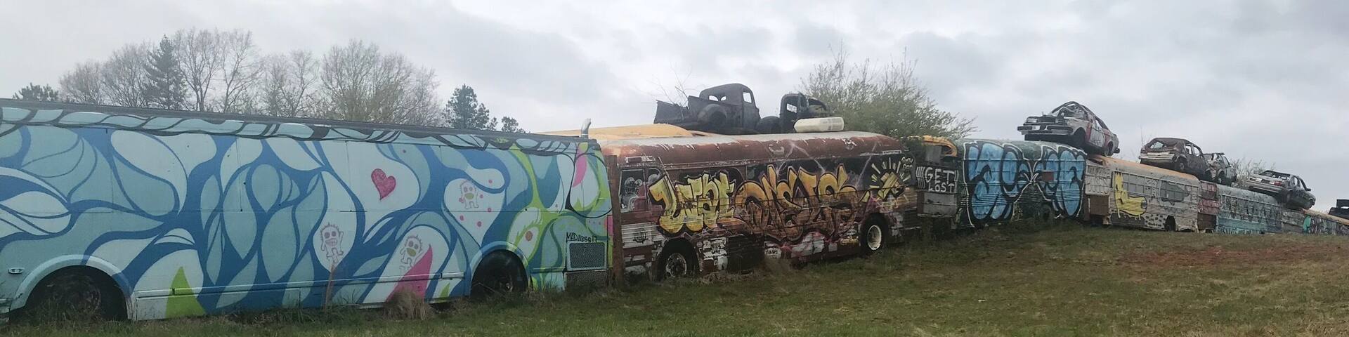 The painted school buses form a fence around a junk yard. Be aware that you just park along the road and go up the hill to get there. I think you can tour the yard but itâs only open mon - fri 8-5 pm.