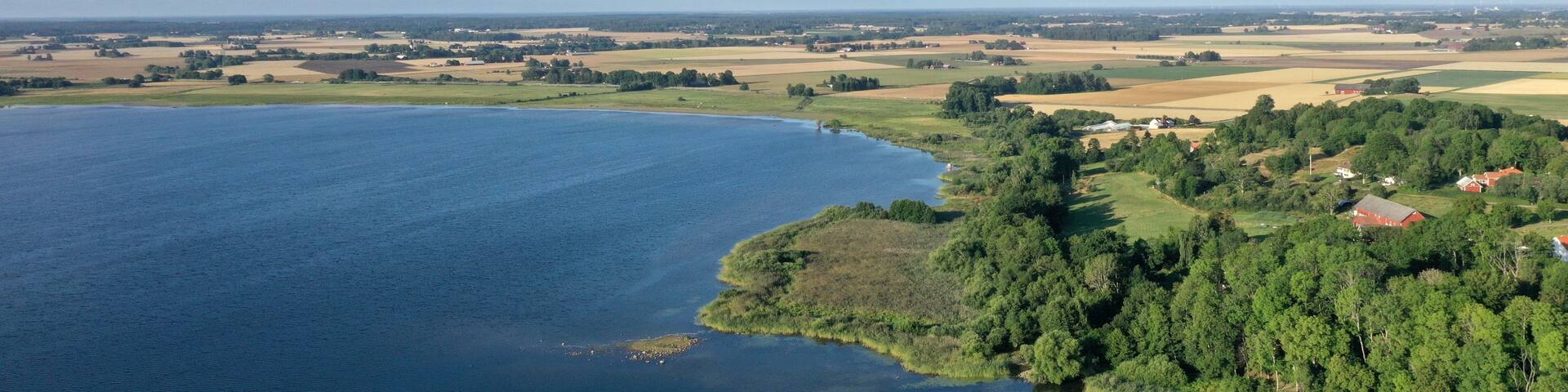 A river meandering through a landscape with fields, trees, and a few buildings.