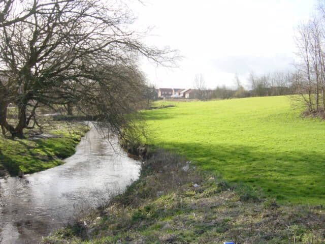 Kirkby Brook looking South. Kirkby Brook joins Mill Brook and flows into the River Alt. The photograph was taken looking south near Bewley Drive which was originally called Cat Tail Lane where there was a farm of the same name. The houses in the background are in Westvale on the other side of Valley Road.