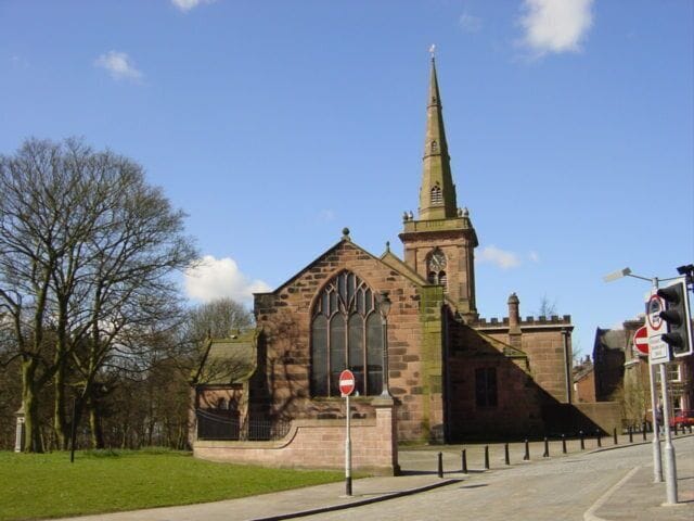 A historic church with a tall spire and large arched windows.