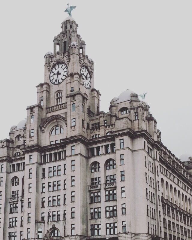 A historic building with ornate architecture, including a clock tower and statues.