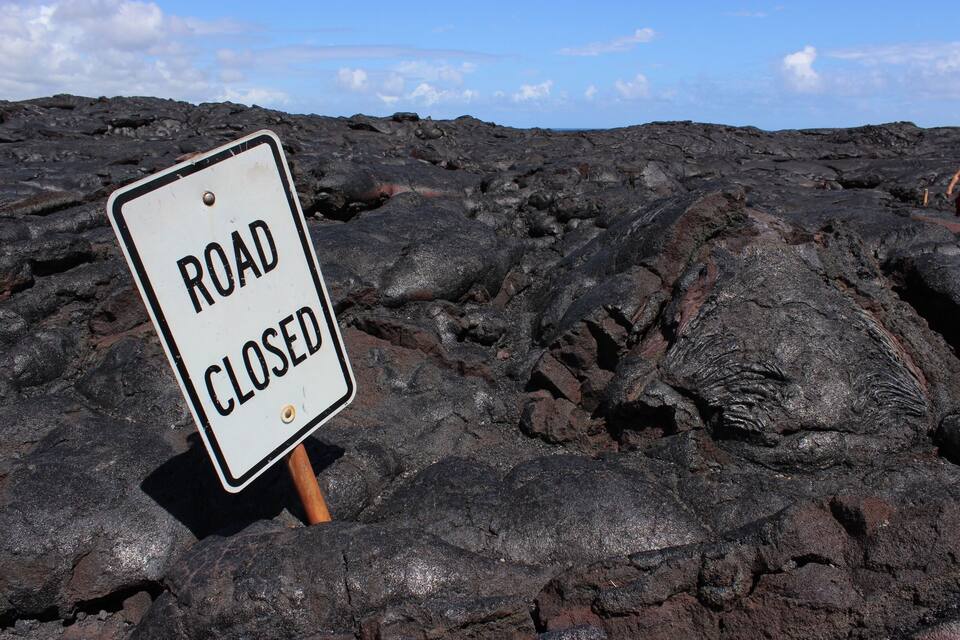 A road closed sign on a rocky terrain.