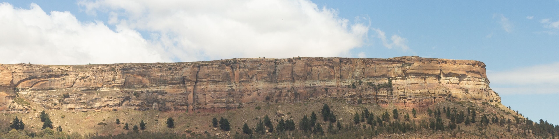A flat-topped butte with sparse vegetation and a clear sky.