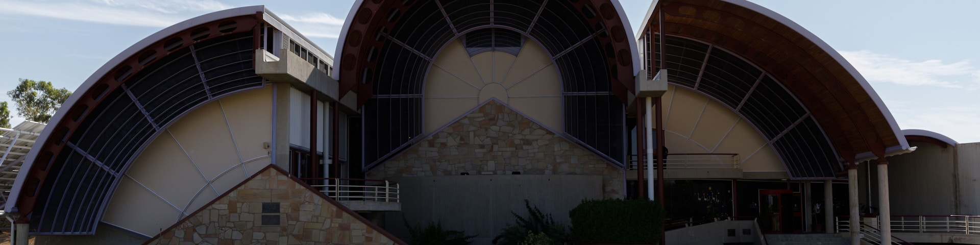 Un edificio moderno con techo curvo y base de piedra, identificado como 'The Australian Stockman Hall of Fame'.