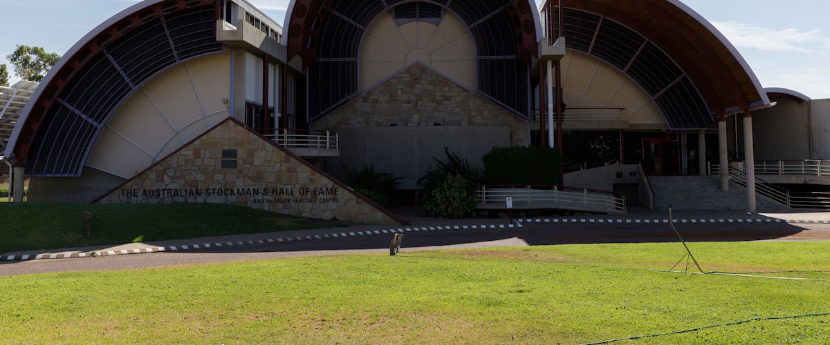 A modern building with a curved roof and a stone base, labeled 'The Australian Stockman Hall of Fame.'