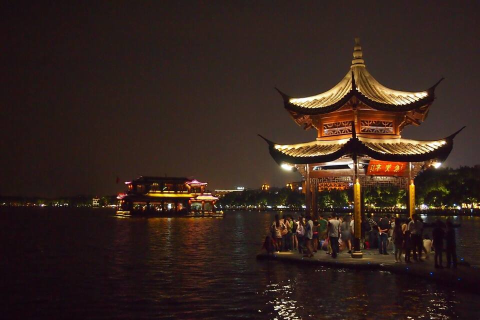 A traditional Chinese pavilion by a body of water at night.