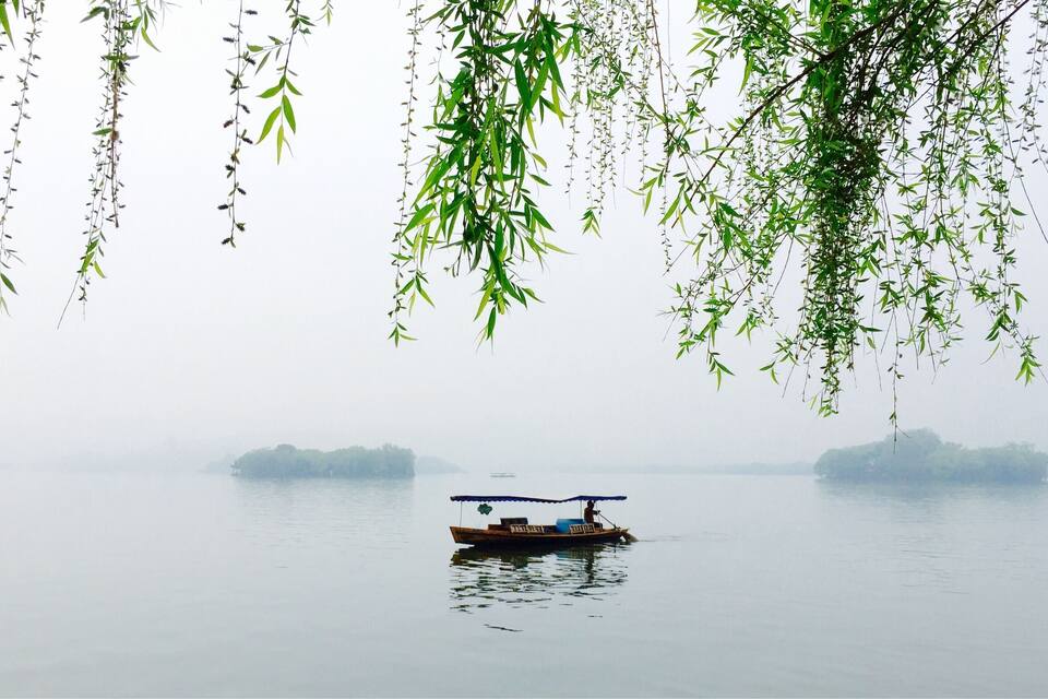 A calm river with a small boat and distant fog-covered islands.