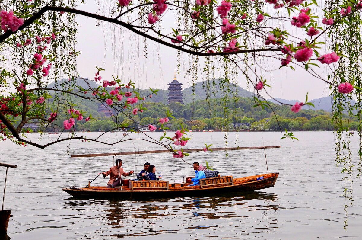 A traditional boat on a calm lake with a pagoda in the background.