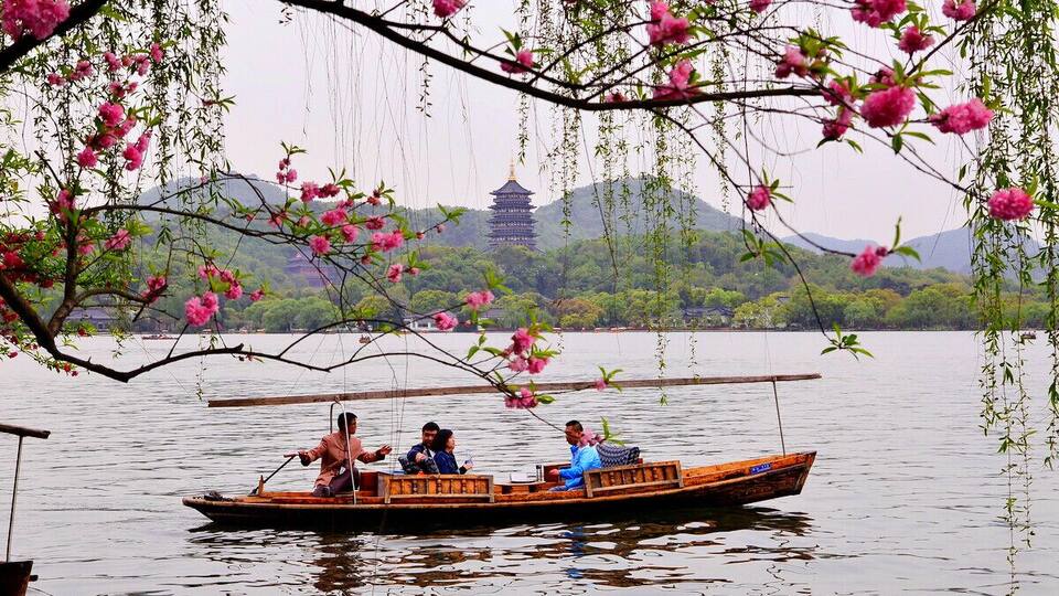 A traditional boat on a calm lake with a pagoda in the background.