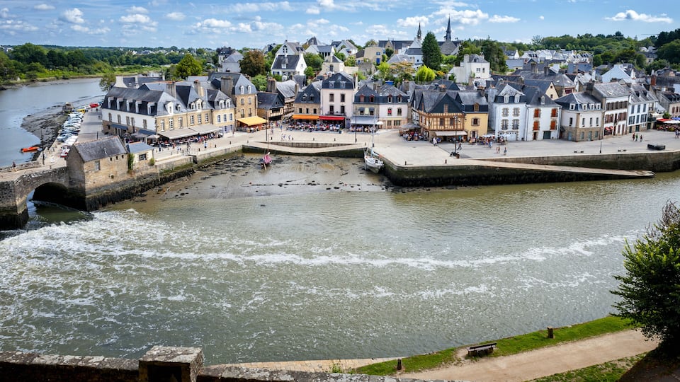 A riverside town with historic buildings, a bridge, and a boat dock.