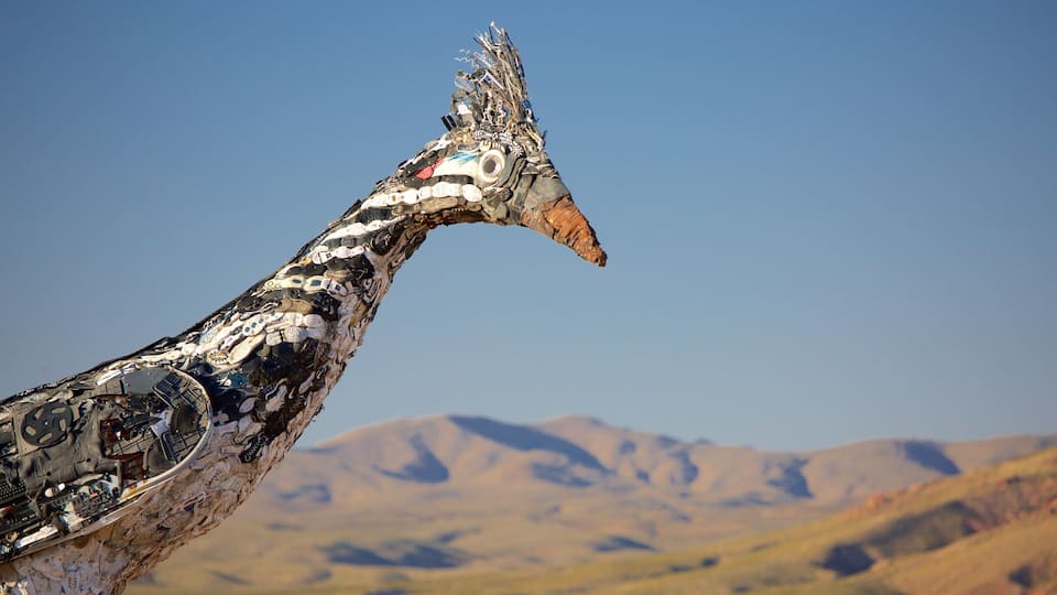 A giraffe with a patterned coat and a mountainous landscape in the background.