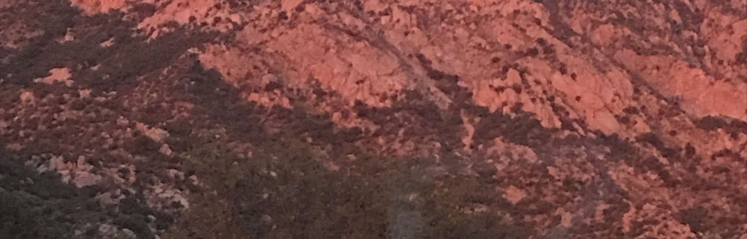 A mountain range with reddish rock formations and sparse vegetation.