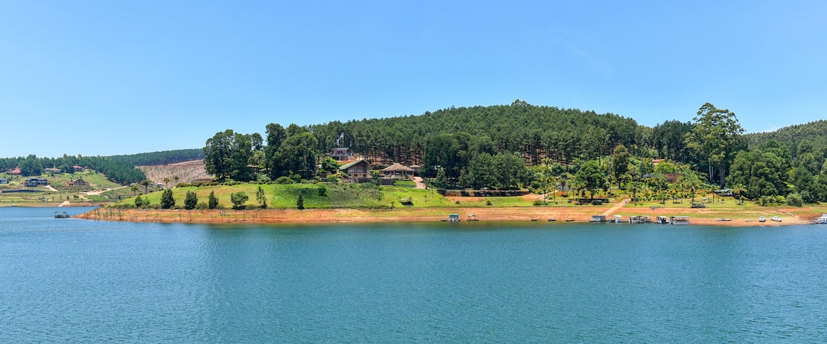 A lake with a forested hill and buildings in the background.