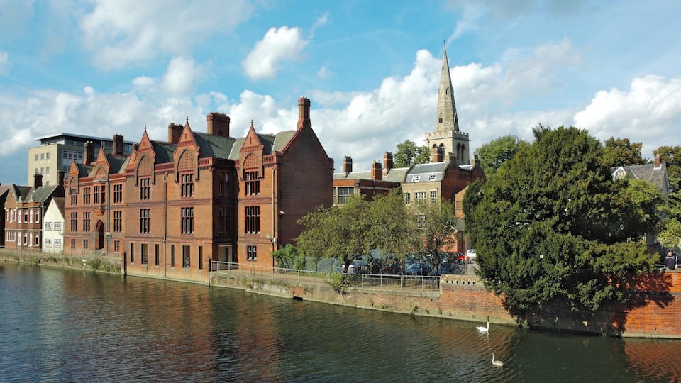 A riverside view of historic buildings and a church steeple.