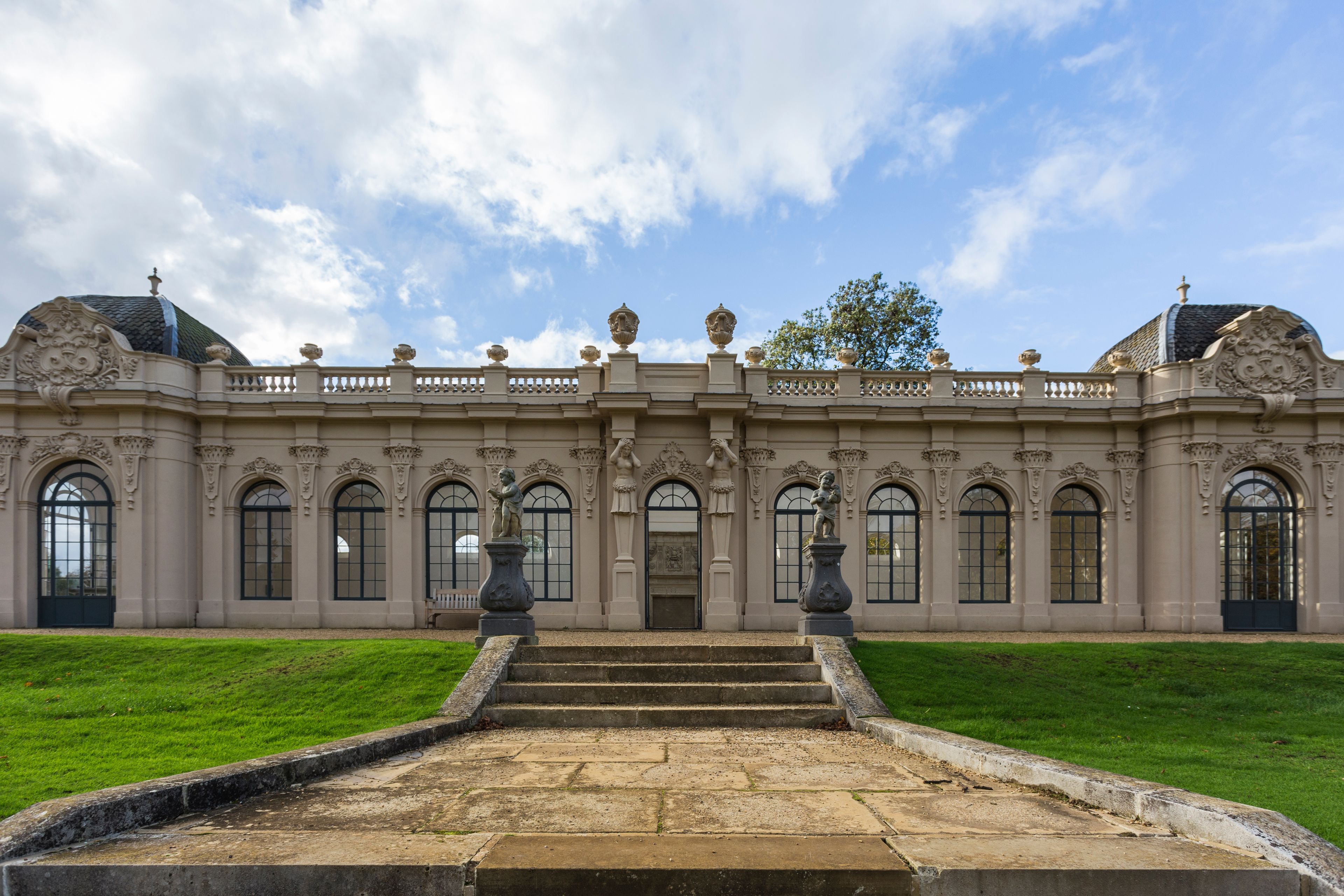 A grand building with ornate architecture, featuring a symmetrical facade, large arched windows, and statues.