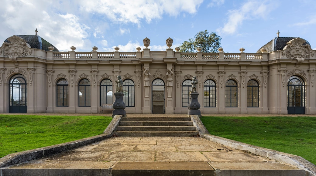 A grand building with ornate architecture, featuring a symmetrical facade, large arched windows, and statues.