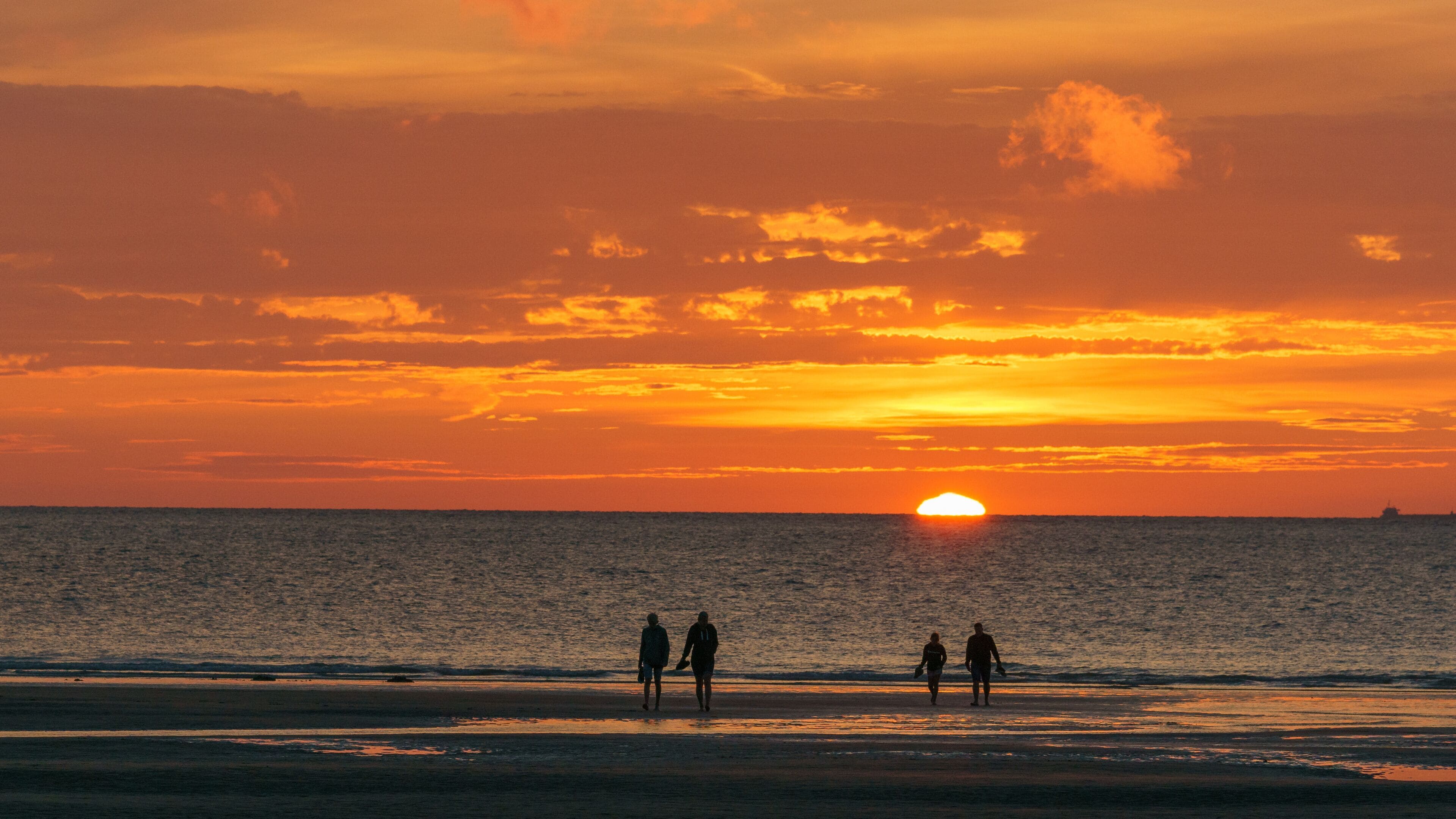 Silhouette of a group of people walking in front of the north sea on the beach during sunset, Opal Coast, Wissant, France