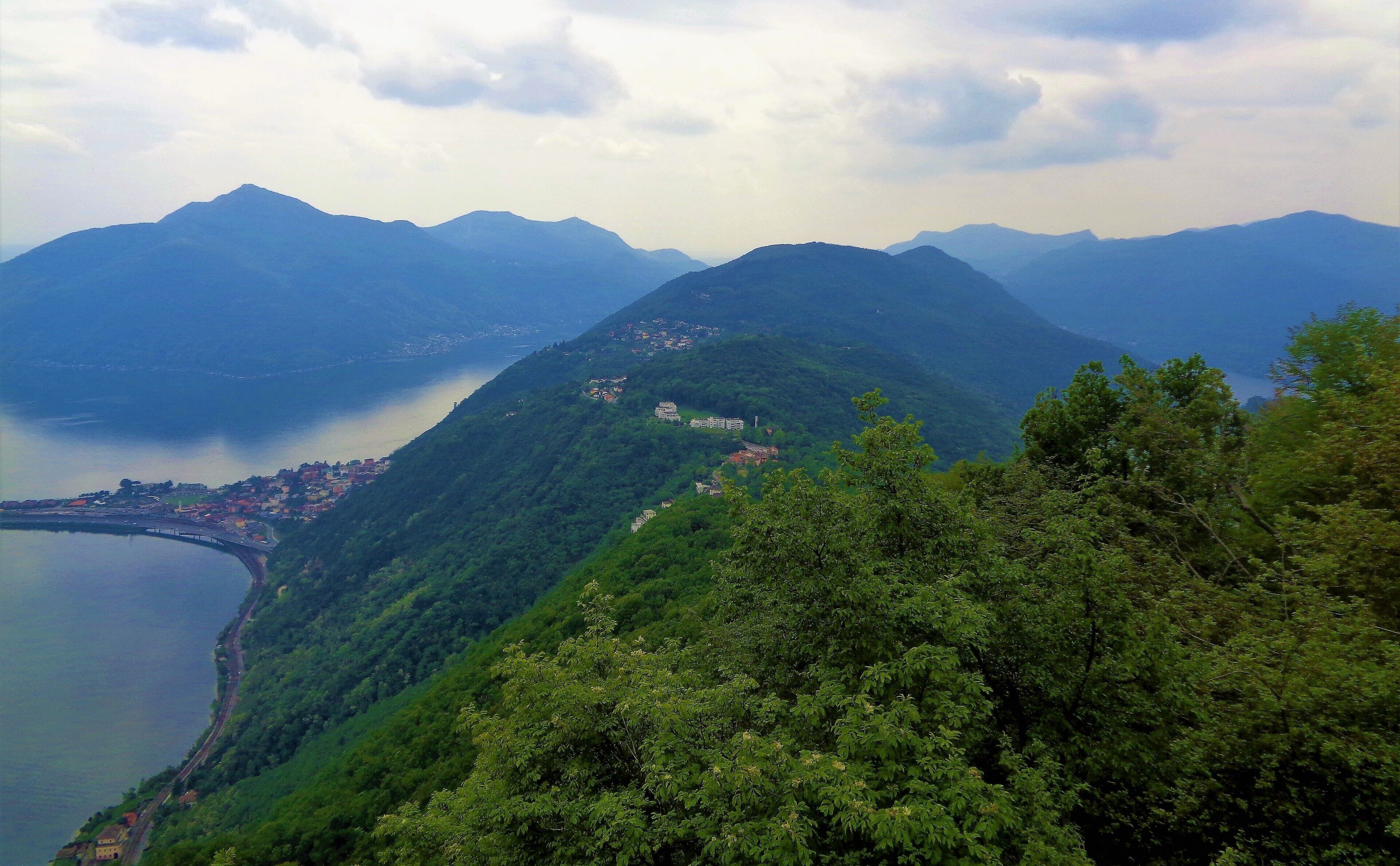 I took this photo from Monte San Salvatore in Ticino, Switzerland. It was a beautiful Spring moment! This spot gives great views of the mountains surrounding Lake Lugano! Usually, it is sunny and clear from here, but on that day, my only day on Monte San Salvatore, I got an atmospheric experience! And Monte San Salvatore is above the city of Lugano, so it's quite easy to get there!
