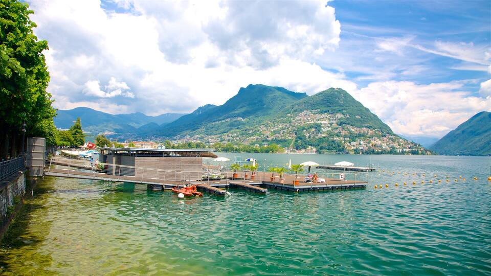 A lakeside pier with boats, a wooden building, and a mountain backdrop.