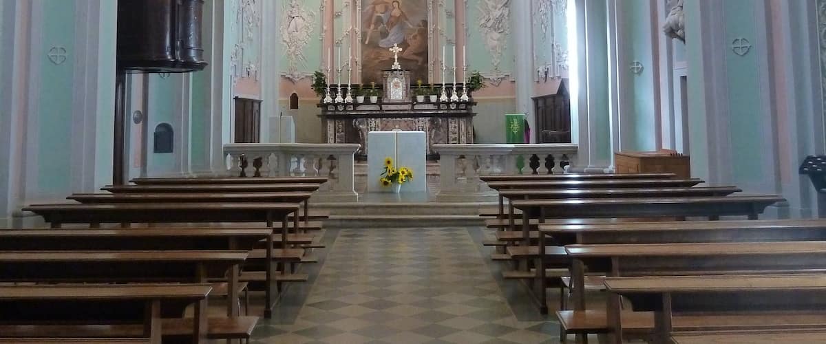 An ornate church interior with a checkered floor, wooden pews, and a central altar.