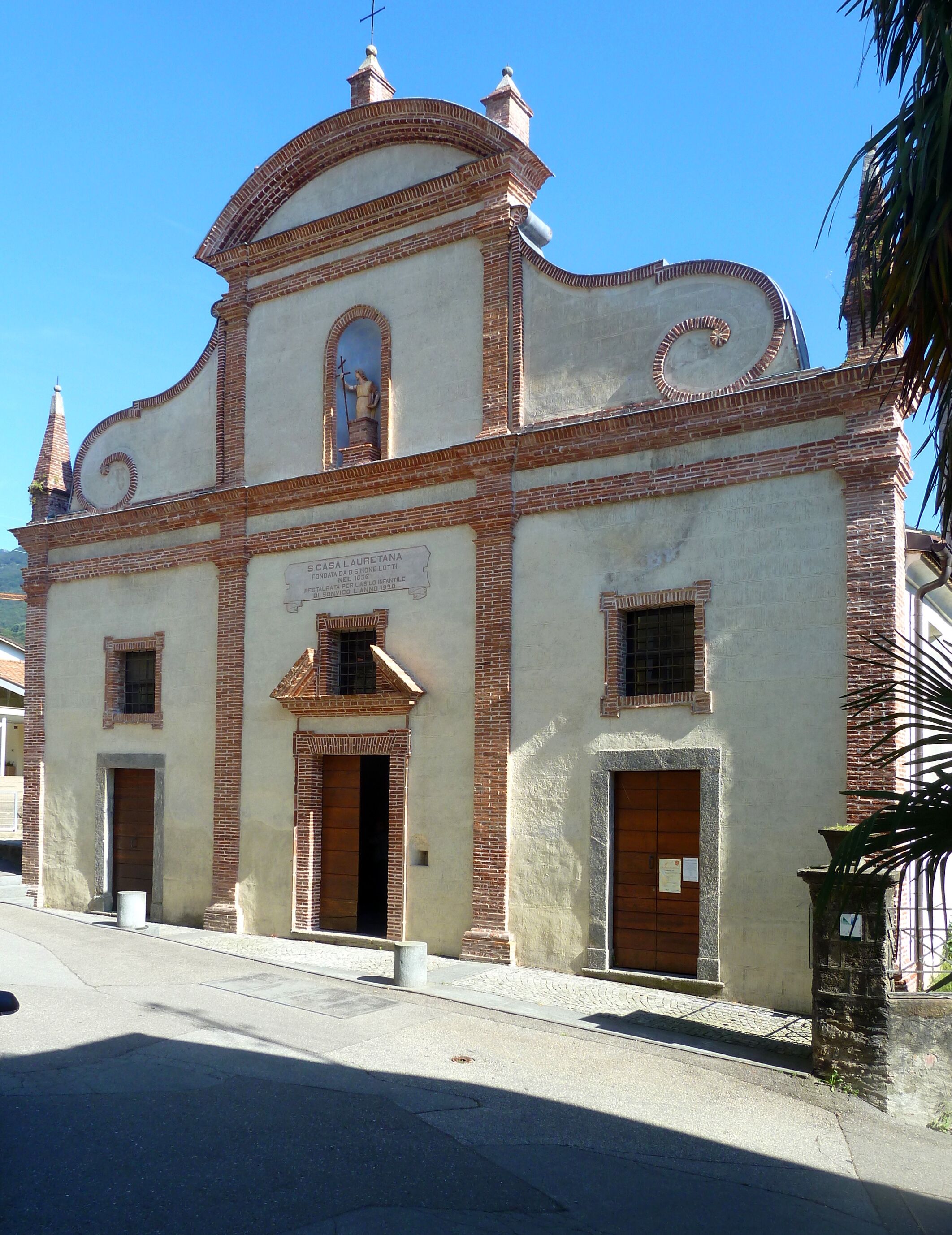 A historic church with a cross on top, a bell tower, and a sign indicating it is the birthplace of a famous historical figure.