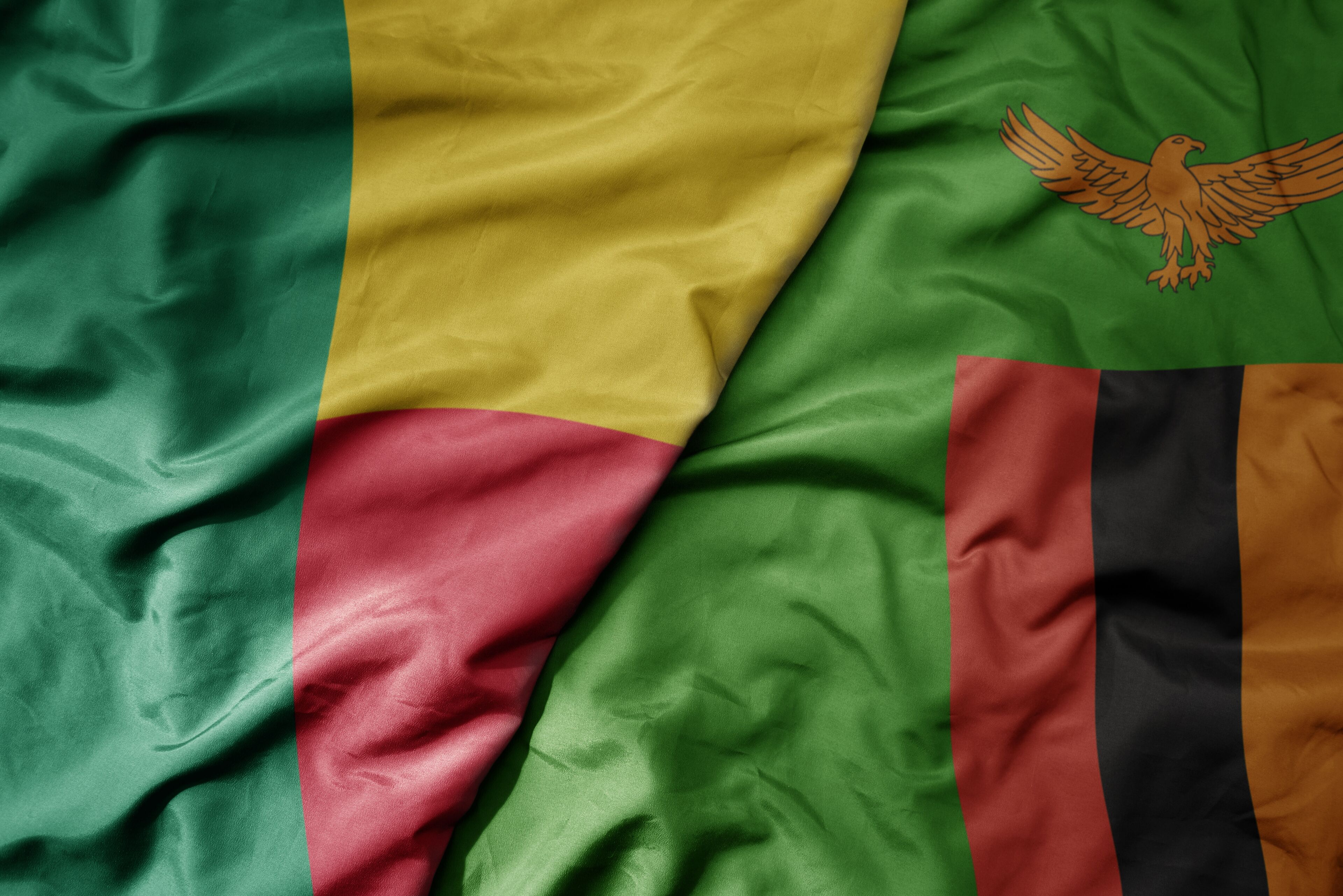 big waving national colorful flag of benin and national flag of zambia .