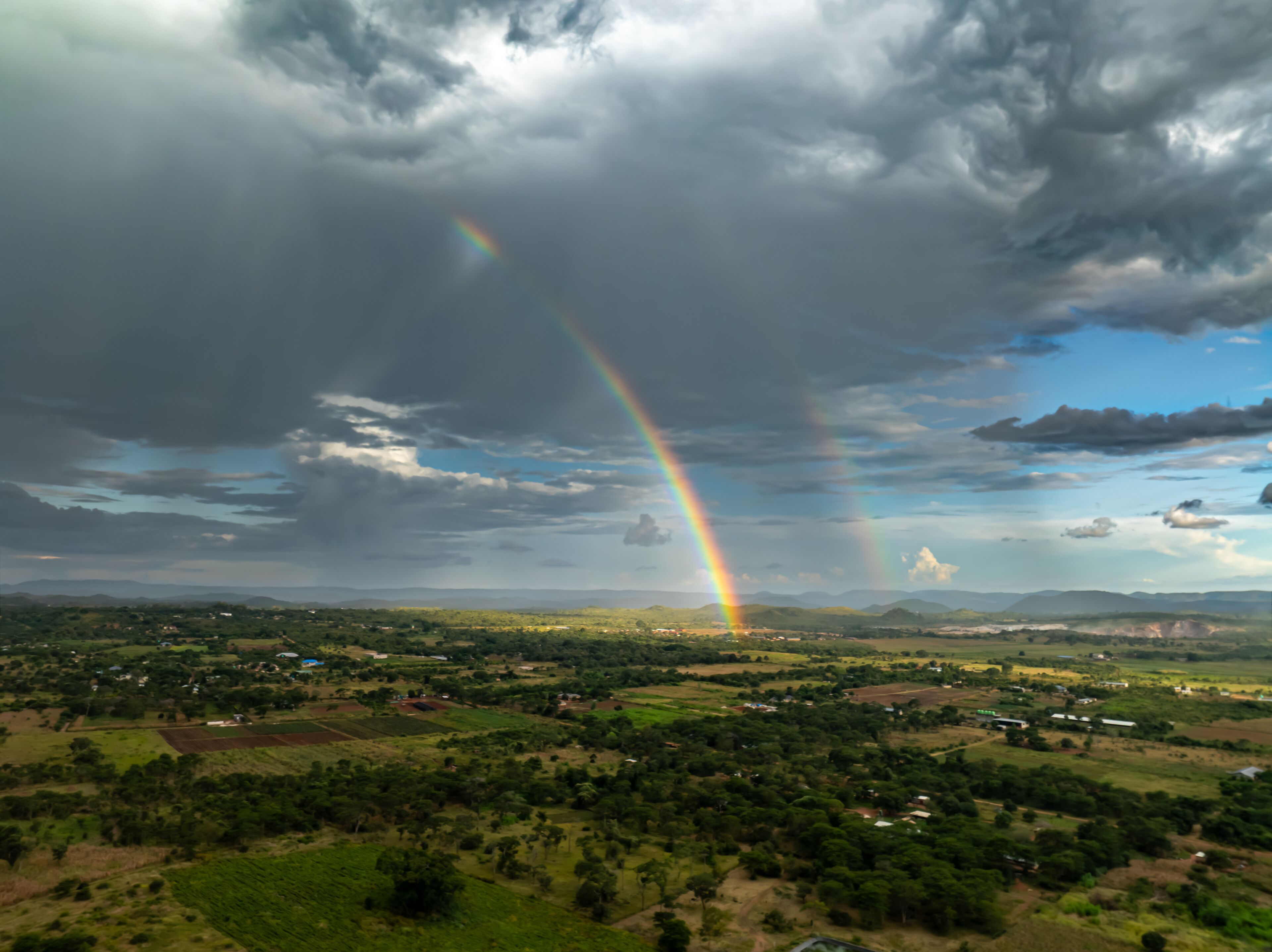A landscape with a rainbow, green fields, and scattered houses.