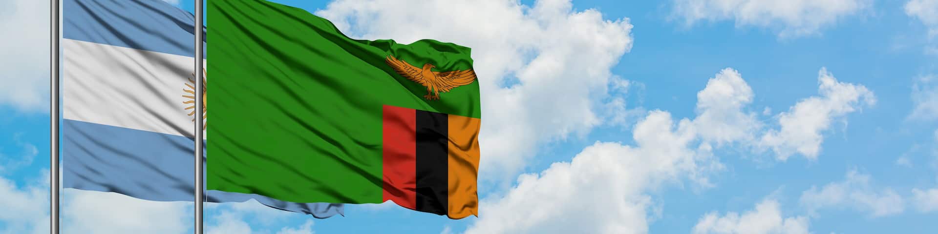 Argentina and Zambia flag waving in the wind against white cloudy blue sky together. Diplomacy concept, international relations.
