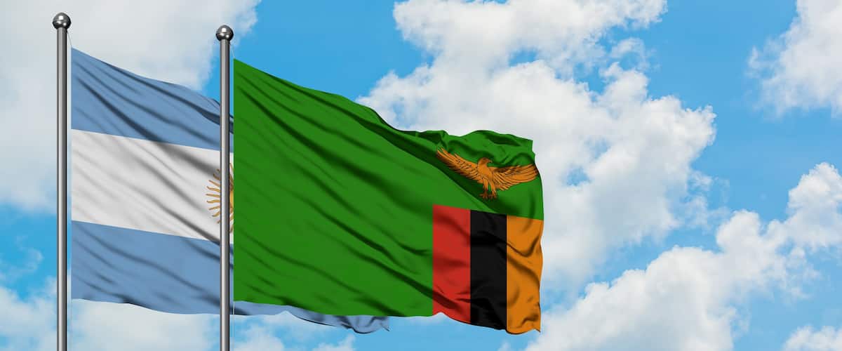 Two flags waving against a blue sky with clouds.