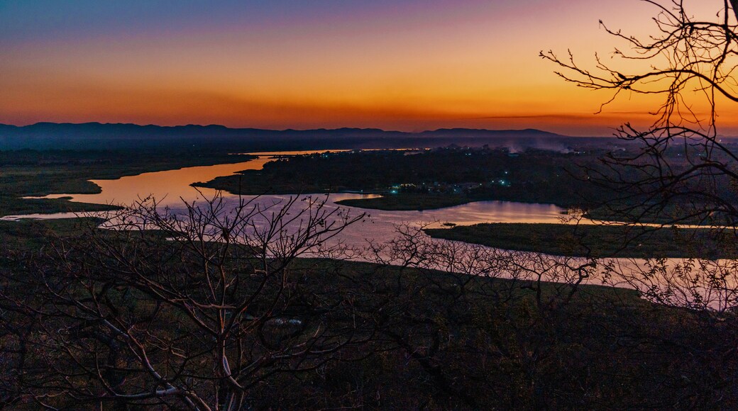 Kafue, Lusaka Province, Zambia - 19 July 2026: Aerial view of the Kafue River winding through the landscape at sunset with silhouettes of trees in the foreground and a vibrant orange sky.